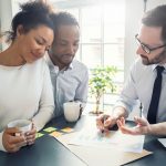 Three people sit together and discuss estate planning documents.