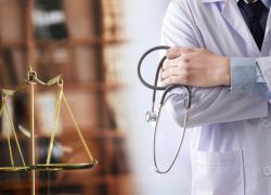 A doctor holding a stethoscope stands next to the scales of justice.
