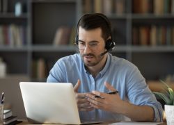 A person with a headset is looking at a computer and working somebody through the Legal & Financial Navigation Program