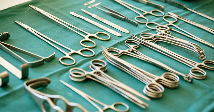 Surgical tools on a green surgical sheet, representing breast explant surgery.