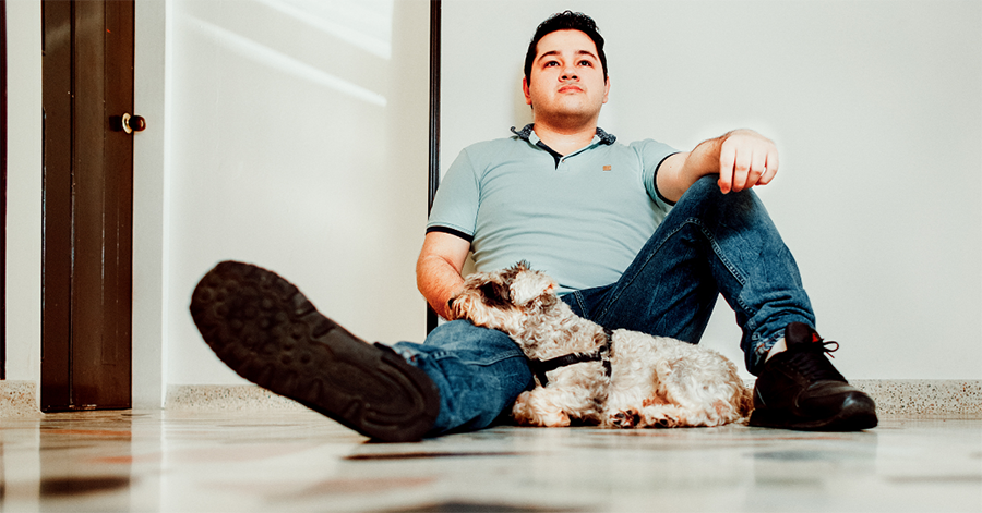 A man sits on the floor with his dog, representing caregiver self-care