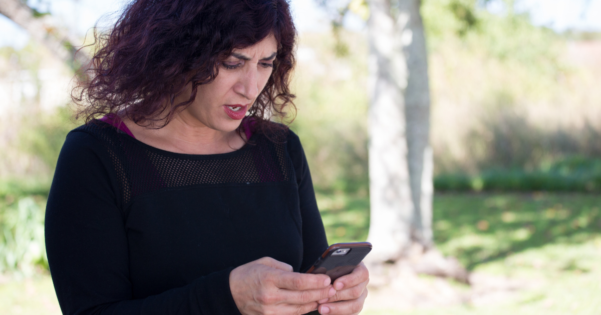 A shocked woman looks at her phone, wondering what to do when a debt collector contacts you.
