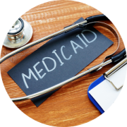 A black piece of paper has the word "Medicaid" written on it, and a stethescope on top of it, representing the medicaid 101 and other benefits webinar.