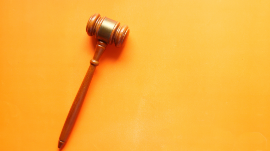 A gavel rests on a yellow background.