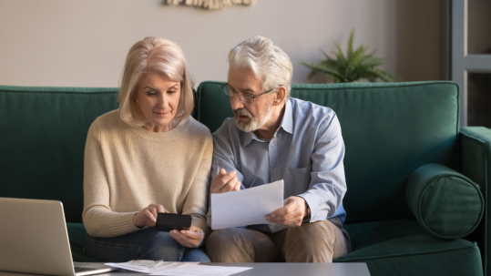 An older couple discusses Medicare and HSA while sitting on the couch.