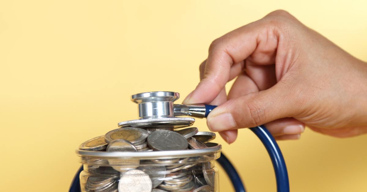 a person holds a stethoscope over a jar of coins - representing a health savings account