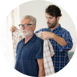 A young man helps his elderly father put on a jacket