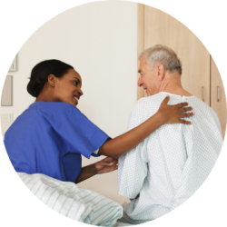 A nurse in blue scrubs helps a patient get out of bed