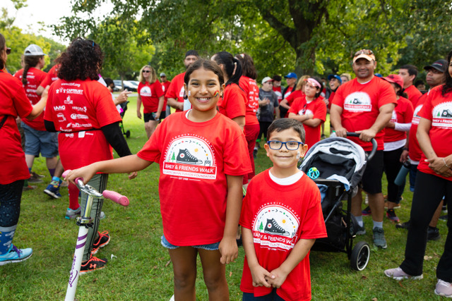 Two children in bright red t-shirts stand together at a Children's Brain Tumor Foundation event.