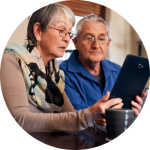 An elderly couple looks at health insurance options on the tablet.