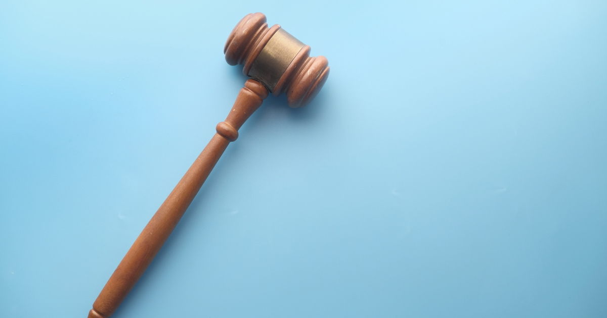 A wooden gavel sits on a sky blue background