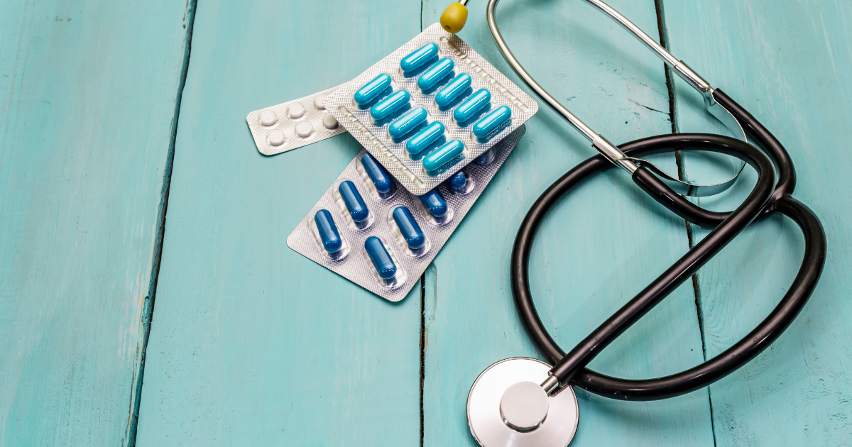 A stethoscope and several medications sit on a blue background.