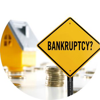 A yellow sign that says "bankruptcy" sits in front of the image of a house and coins stacked on the ground.