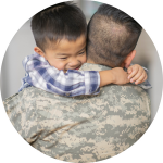 A man dressed in a military uniform hugs a young child