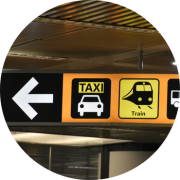 A transit sign with a taxi and train icon, that points to the left.