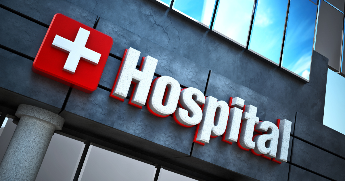 The front of a hospital with the white cross on a red background.