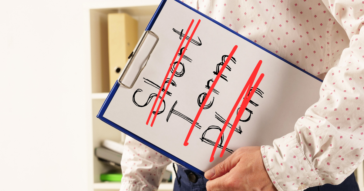 A person wearing a white shirt with pink dots is carrying a clip board with a piece of paper that says "short term plan" and the words are crossed out in red.