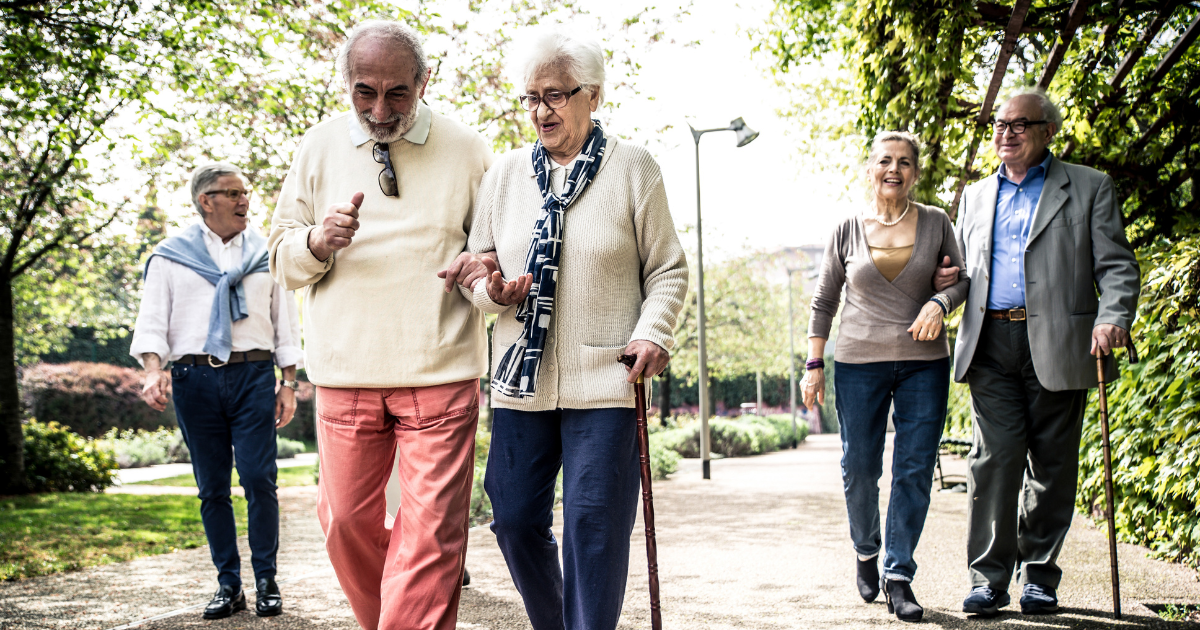 Several older couples walk down a path together.