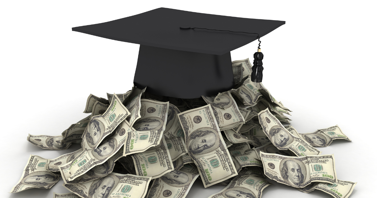 A graduation cap sits on a pile of one hundred dollar bills.